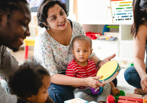 Parents and young children play together in a colorful room, engaging with musical toys and educational activities.